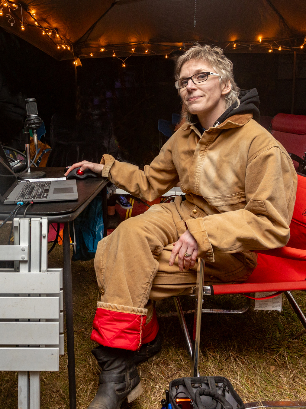 A view of a portable workstation set up in the forest, containing a laptop, microphones, mixer, speakers, and other equipment.